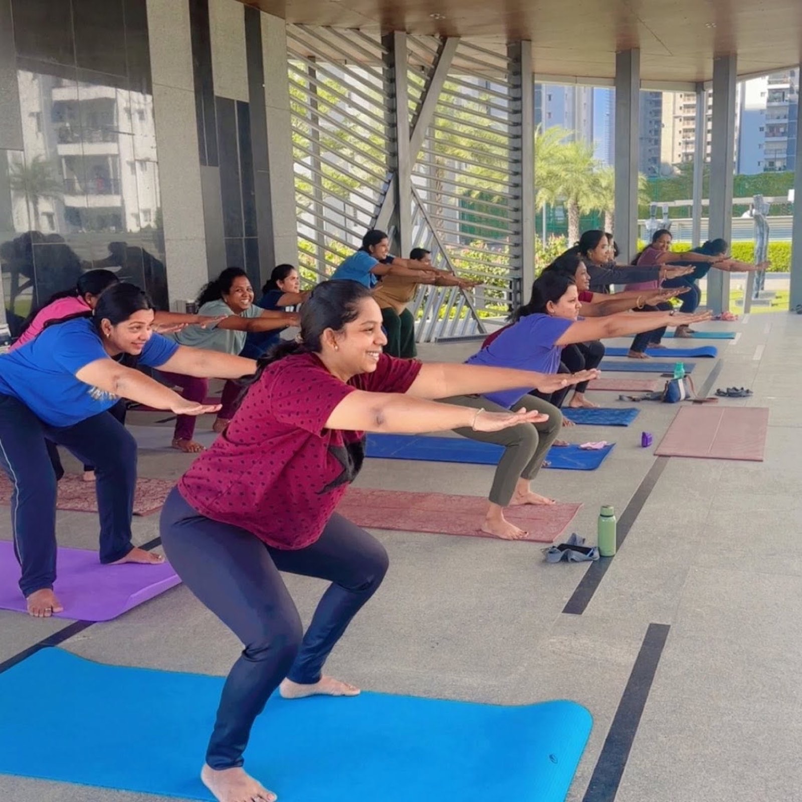 A full class holding chair pose together in the pavilion