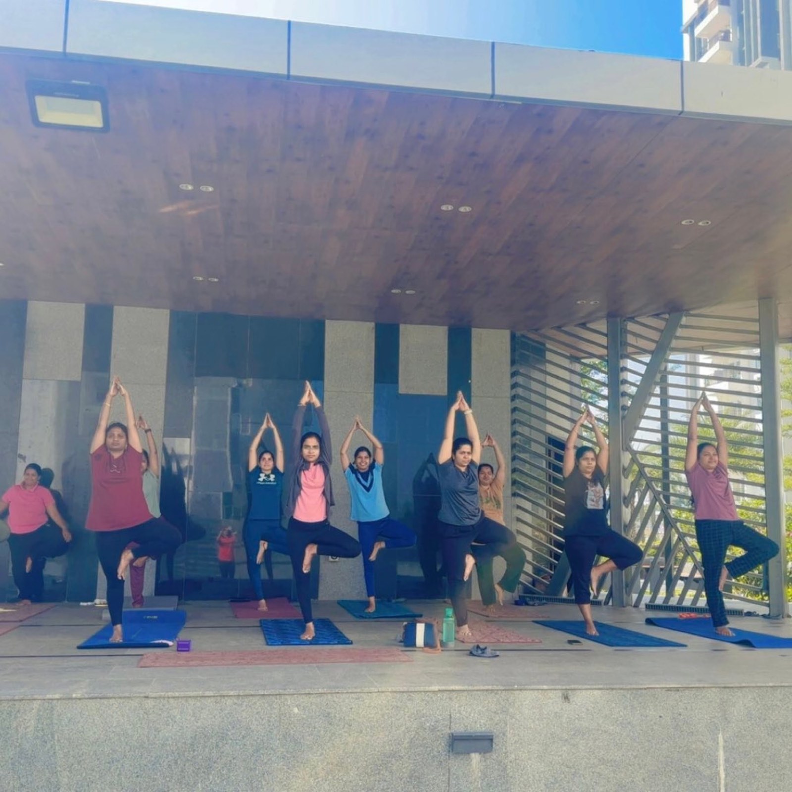 A group holding tree pose together in the pavilion
